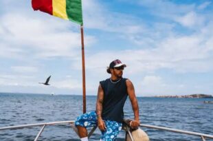 Emu par sa visite à la maison des esclaves sur l'île de Gorée, Lewis Hamilton pose dos à la mer et au drapeau du Sénégal